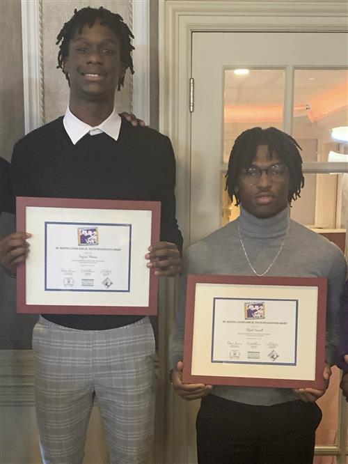 Two males standing together, posing with their framed certificates.